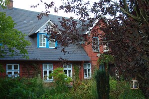 A two-story house with a sloped roof and a brick exterior. - Hotel - Pension ALTES PASTORAT (Langenhorn)