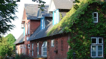 Traditional brick house with a steeply pitched roof, featuring multiple windows and a charming garden.