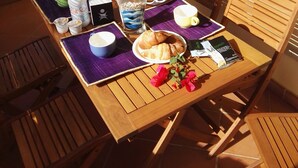 A wooden table with breakfast items, a lamp, and a view of a house and mountains. - Il Mirto apartment (Monte Petrosu)