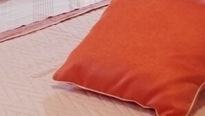 A bed with a quilted cover, an orange pillow, and a decorative white blanket with lace details. - Il Mirto apartment (Monte Petrosu)