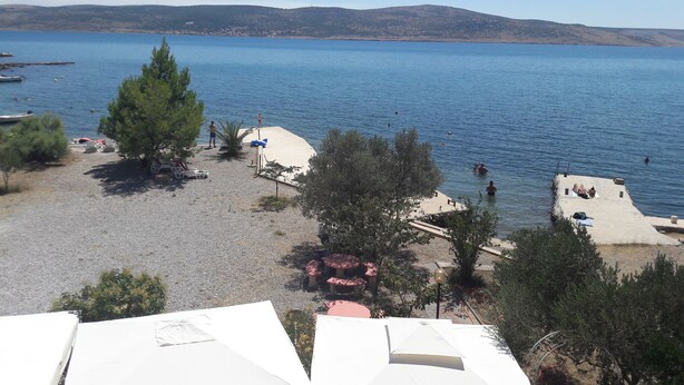 A beach with a clear view of the sea, a few people, and some trees. - Apartments and rooms Marko (Starigrad)