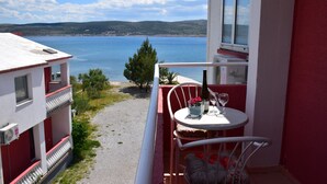 A balcony with a table and chairs, overlooking a body of water and hills. - Apartments and rooms Marko (Starigrad)