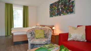 Habitación de hotel con cama, sofá, mesita de noche, lámpara y un cuadro en la pared.