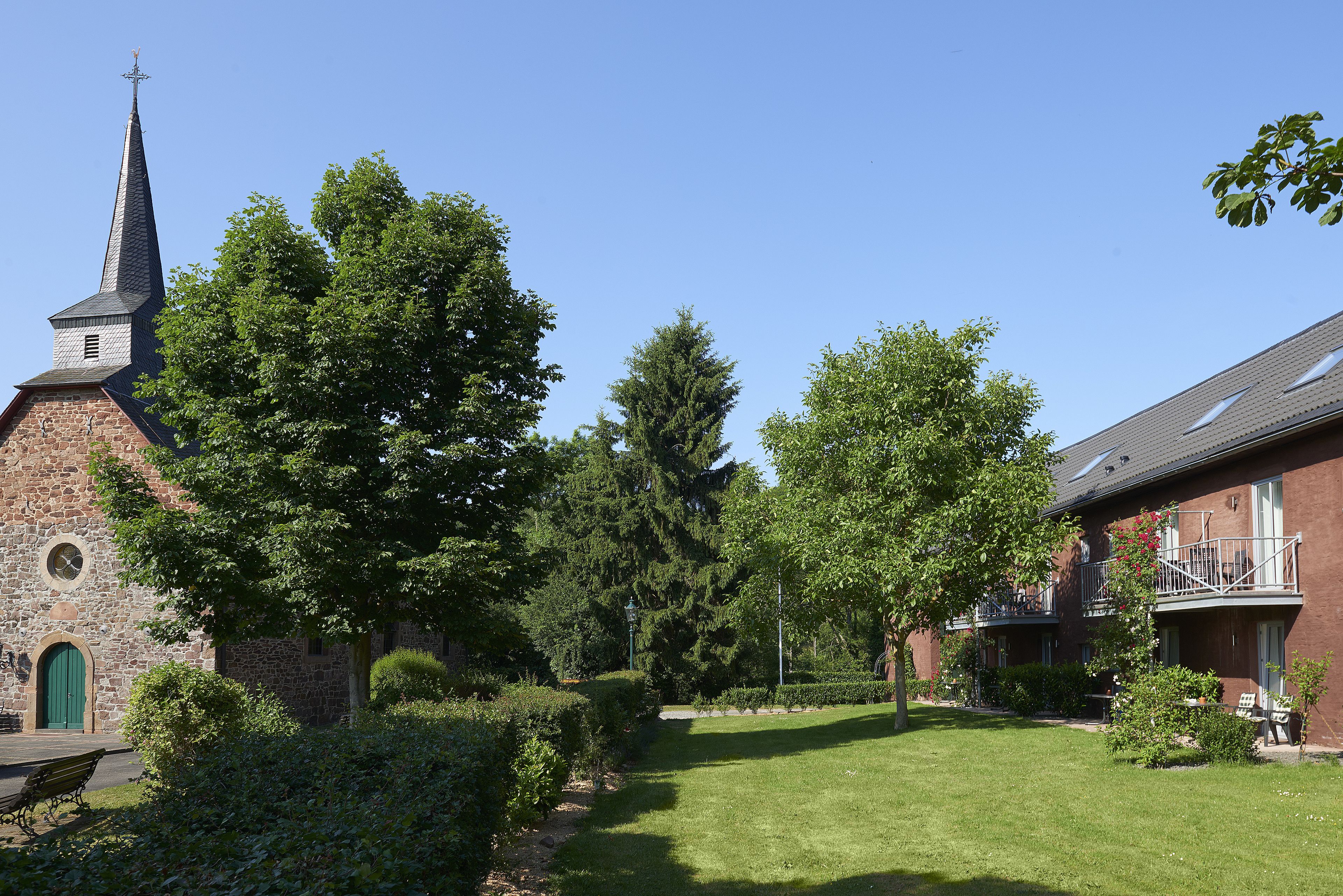 Een binnenplaats met een kerk, een bank en een gebouw met een balkon.
