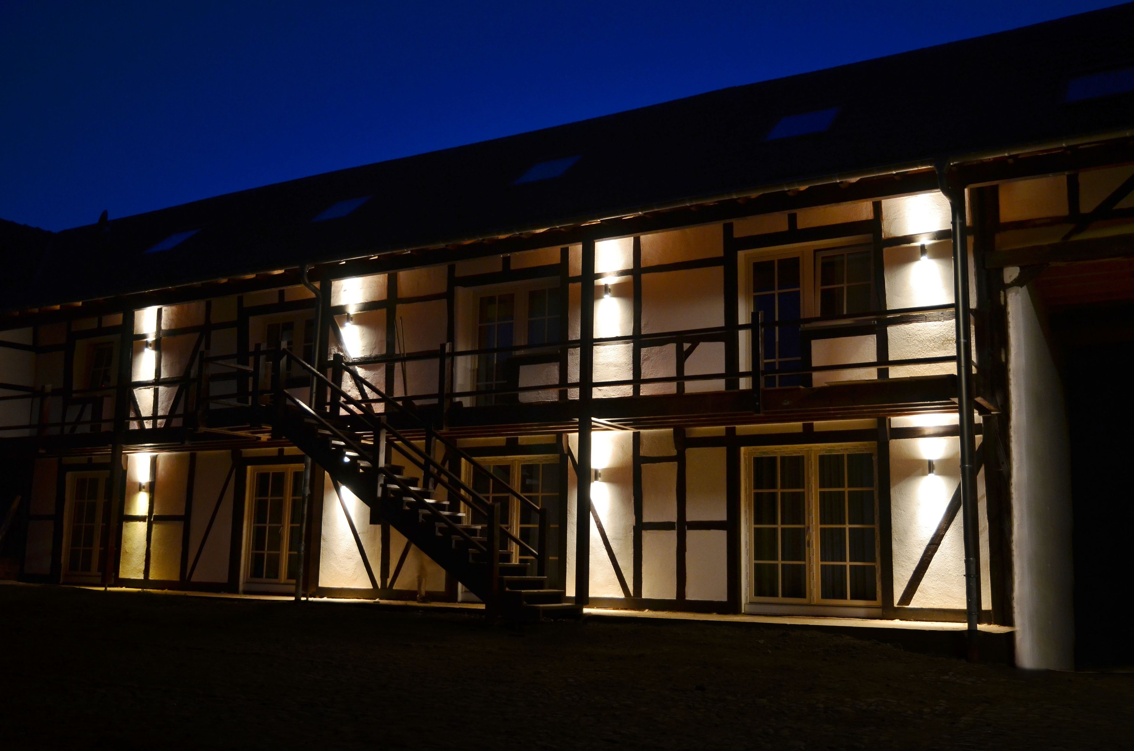 A traditional building with a staircase and multiple windows, illuminated at night.