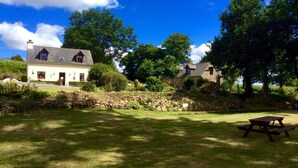 Une maison de campagne avec un mur en pierre et une pelouse verdoyante.