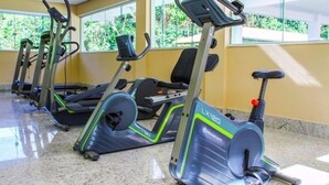 A row of stationary bikes in a gym with large windows and a tiled floor. - Lacqua di Roma (Caldas Novas)