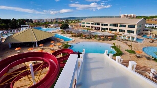 A water park with multiple slides and pools, a covered area, and a building with multiple windows.