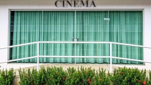 A cinema with a large green curtain and a white railing in front. - Lacqua di Roma (Caldas Novas)