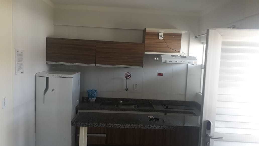 A compact kitchen with a refrigerator, stove, and wooden cabinets.