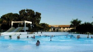 A swimming pool area with a slide and a building in the background.