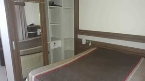 A bedroom with a bed, a wardrobe, a mirror, and a small table.