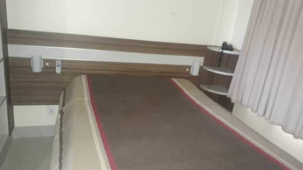 Habitació estreta amb un llit, una petita estant i una cortina.