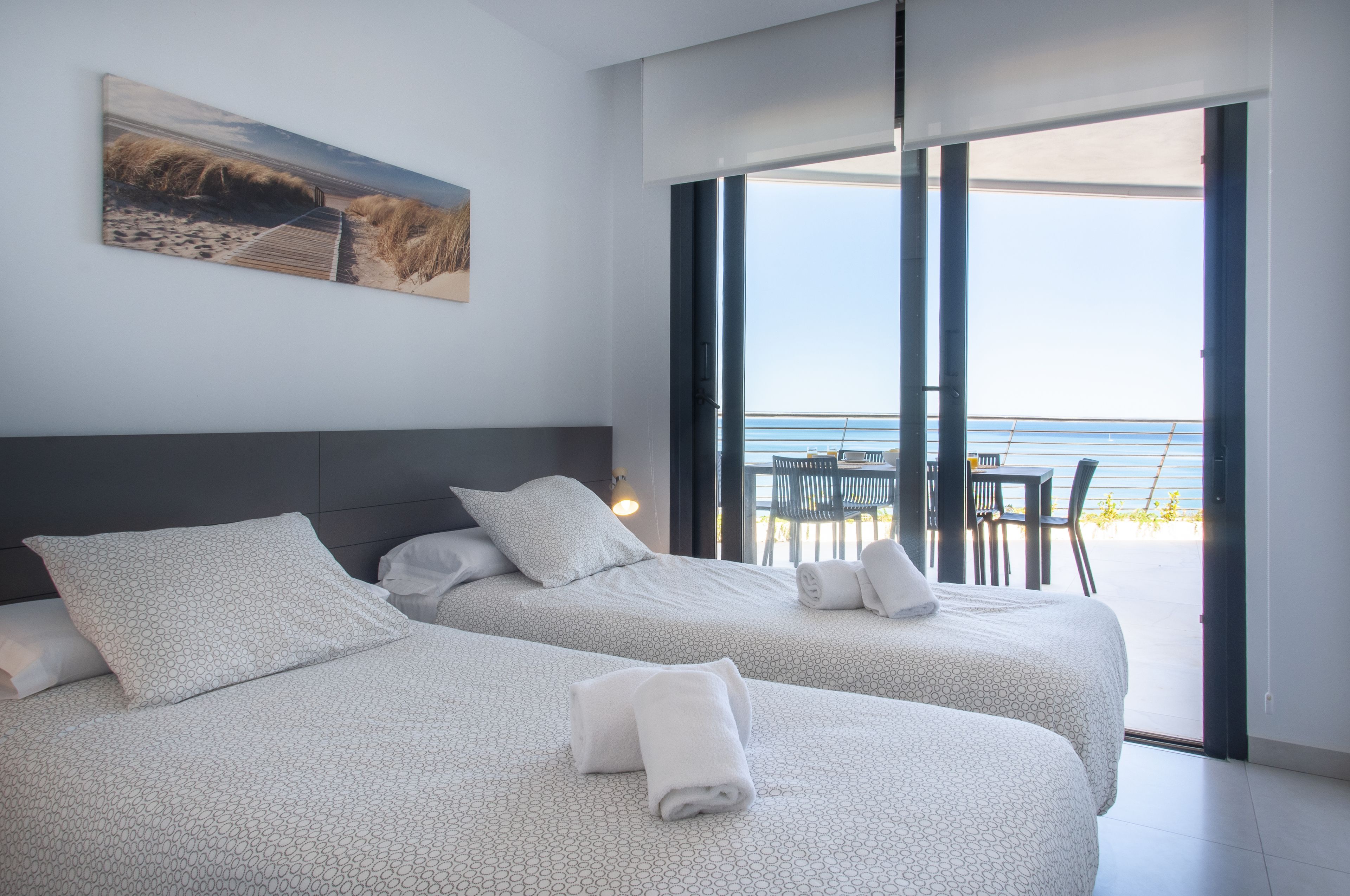 Ein Hotelzimmer mit zwei Betten, einem großen Fenster und Blick auf den Strand.