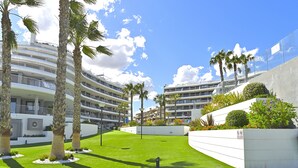 A modern hotel with multiple balconies, palm trees, and a well-maintained lawn. - Myflats Infinity View (Elche)