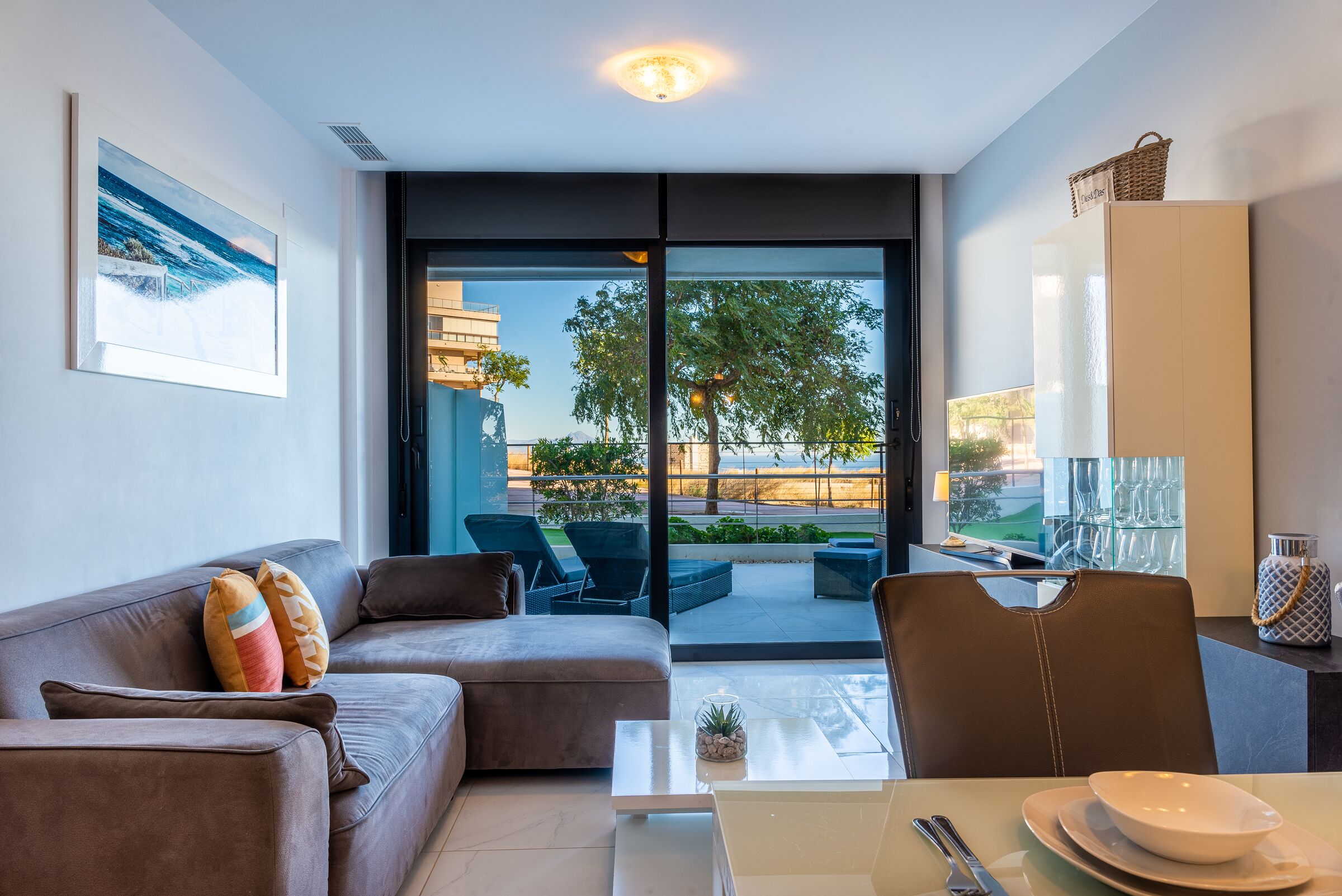 A modern living room with a sofa, a dining table, and a view of the outdoors.