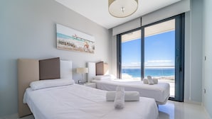 A modern hotel room with two beds, a large window with a view of the beach, and a painting on the wall. - Myflats Infinity View (Elche)