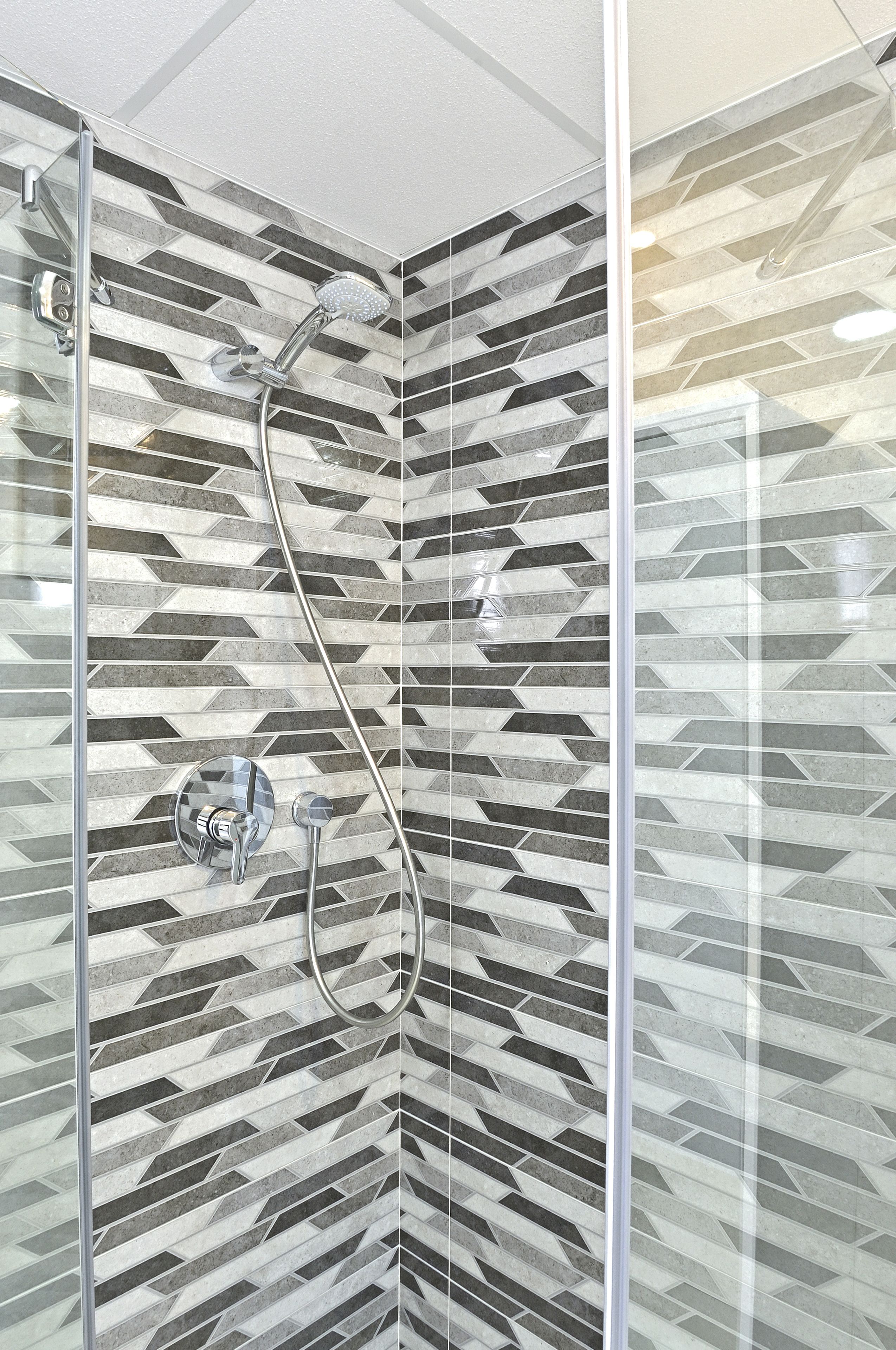 Ducha con un diseño geométrico de azulejos y mampara de vidrio.