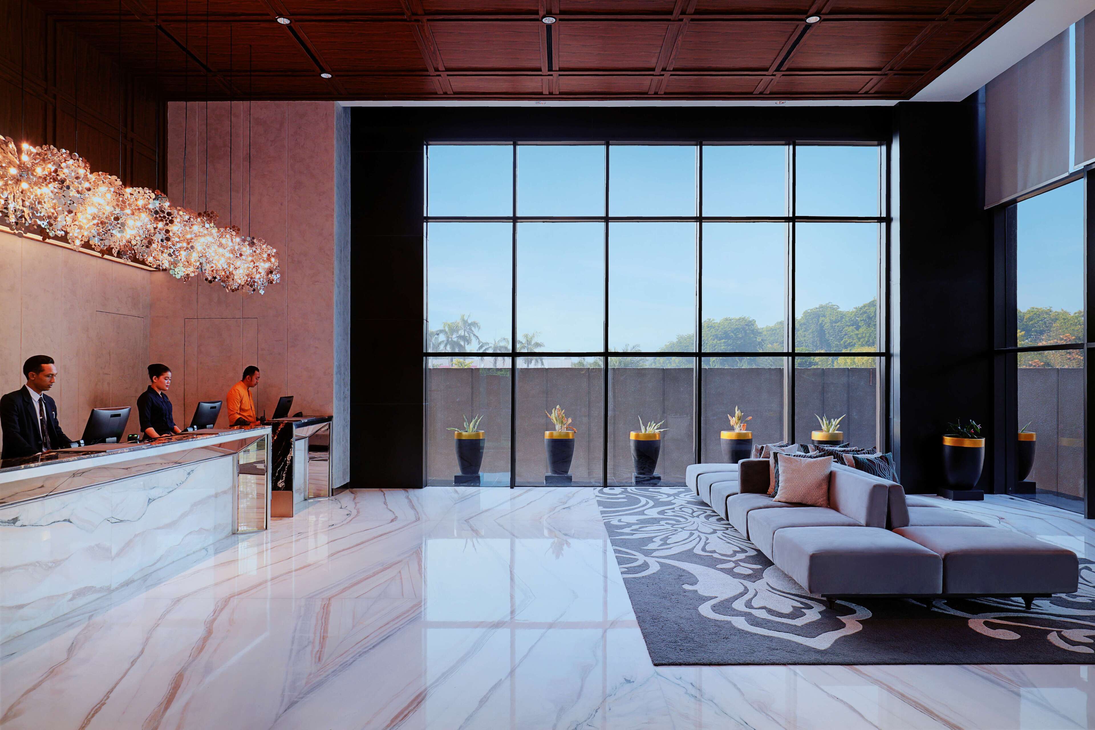 A modern reception area with a marble reception desk, a large window offering a view of the outdoors, and a seating area with a patterned rug.