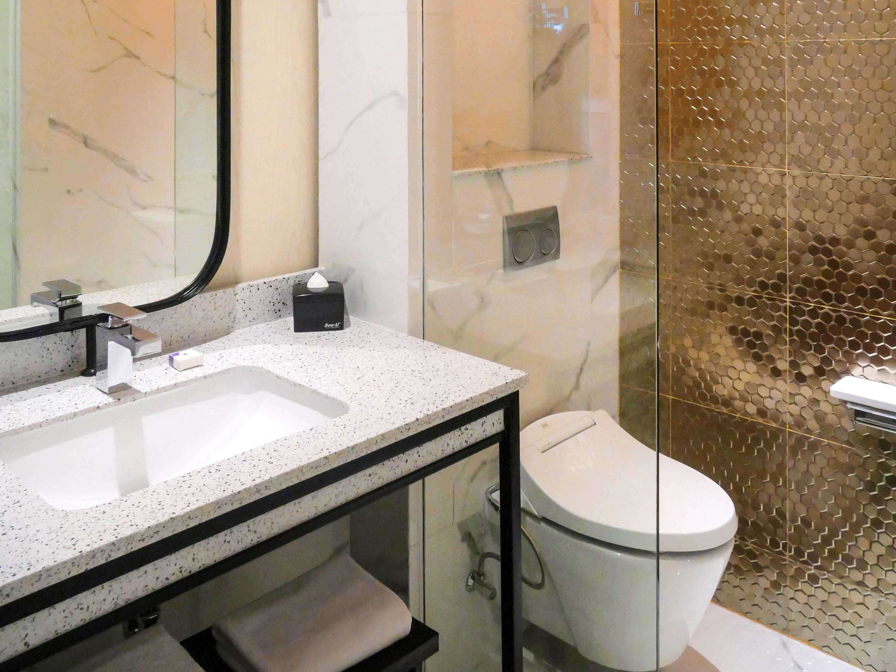 A bathroom with a marble sink, a toilet, and a glass shower enclosure.