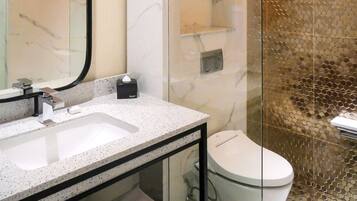 A bathroom with a marble sink, a toilet, and a glass shower enclosure.