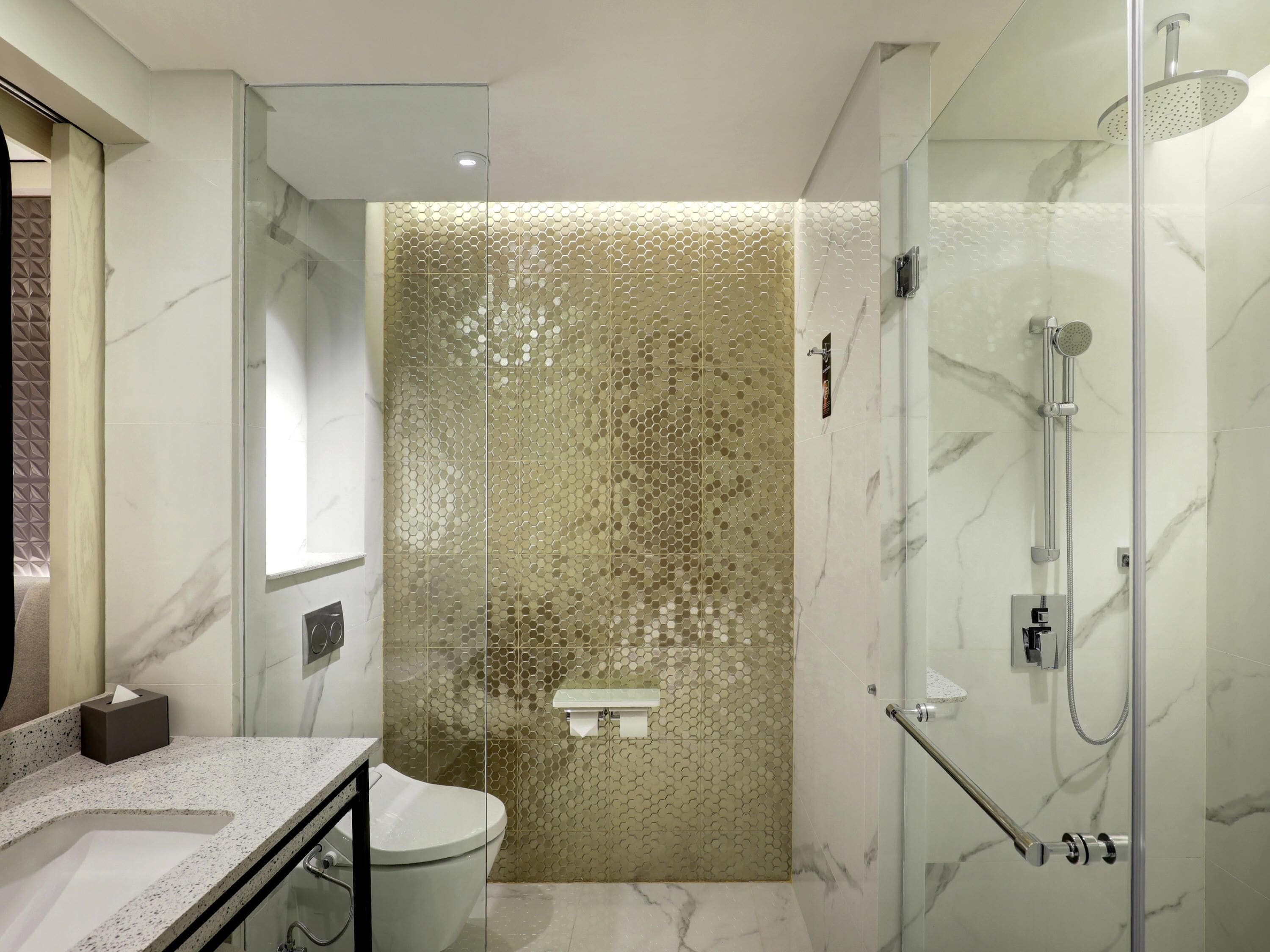 A modern bathroom with a glass shower enclosure, a marble sink, and a toilet.