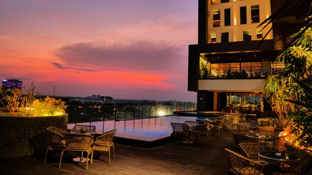 A rooftop bar with outdoor seating and a view of the cityscape at dusk. - Movenpick Surabaya City (Surabaya)