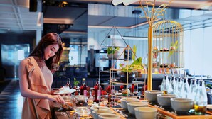 A person serving food at a buffet with various dishes and bottles. - Movenpick Surabaya City (Surabaya)