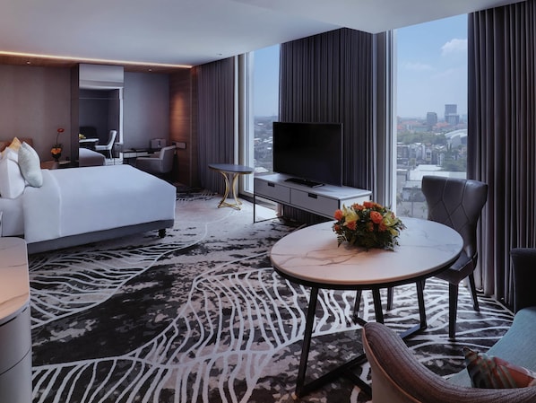 A modern hotel room with a large bed, a desk, a TV, and a view of the city. - Movenpick Surabaya City (Surabaya)