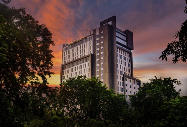 A modern hotel with a prominent 'Grand Mercury' sign, surrounded by lush greenery. - Movenpick Surabaya City (Surabaya)
