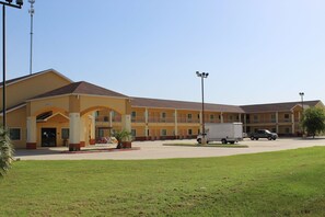 A multi-story motel with a central entrance, a parking lot, and a grassy area in front. - Horizon Inn & Suites - Pearsall (Pearsall)