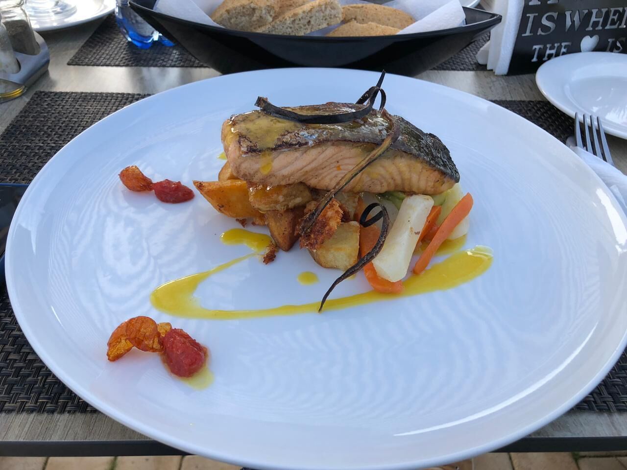 Une assiette blanche contenant un plat de poisson, des légumes et une sauce.