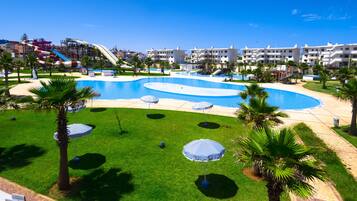 A resort with a large pool, palm trees, and a water slide.