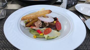 A plate of food with a sandwich, avocado, and vegetables on a table.