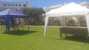 Uma área gramada com uma tenda azul e uma tenda branca.