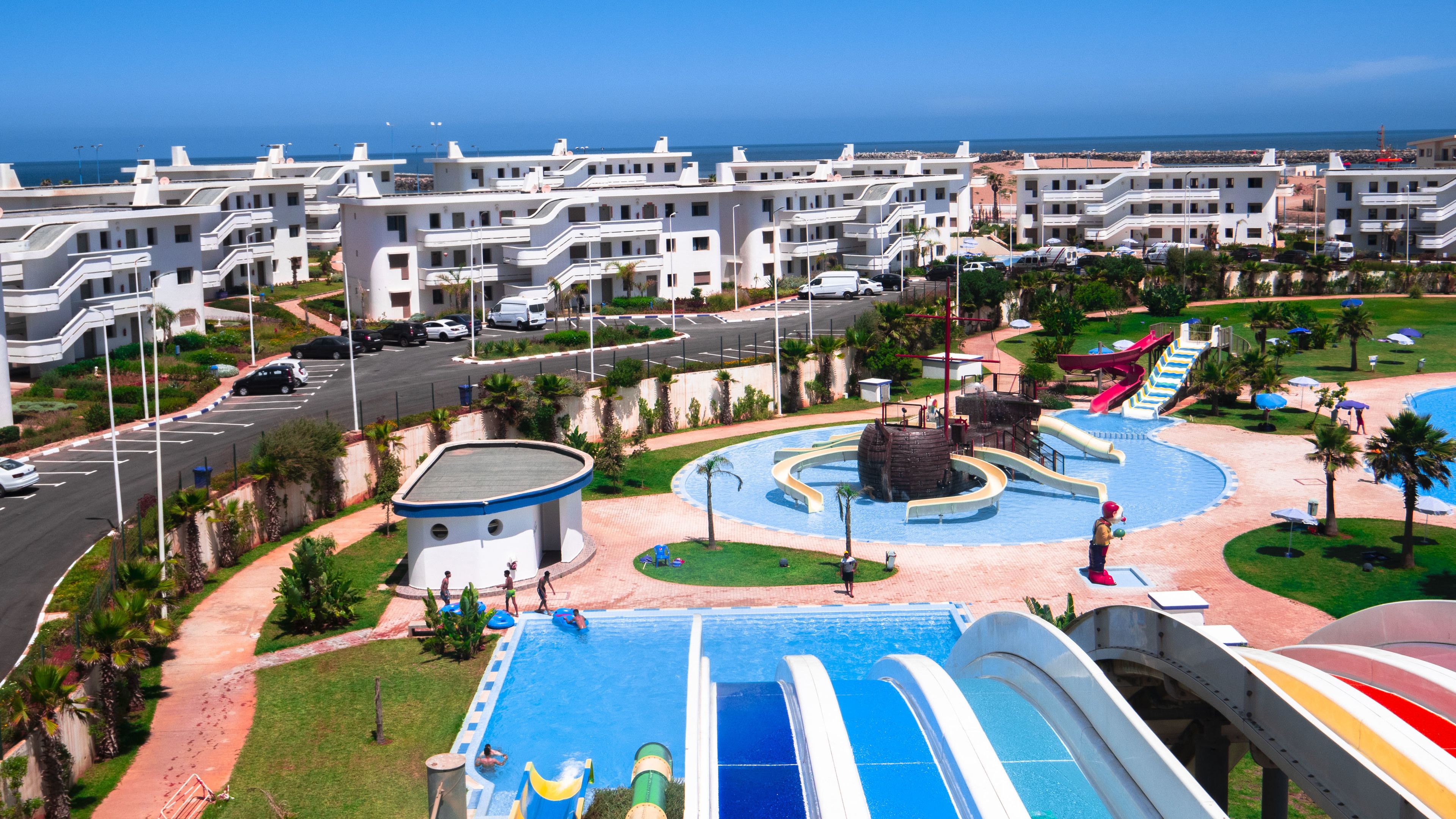 A resort with a pool area, water slides, and a view of the ocean.