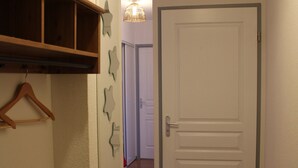Een gang met een witte deur, houten planken en decoratieve items aan de muur.