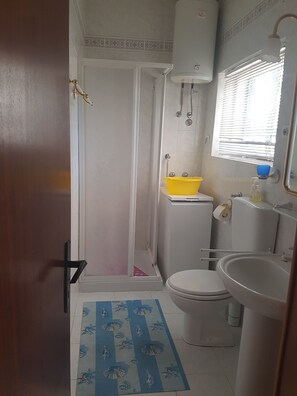 A compact bathroom with a shower, toilet, and sink.