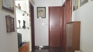 Un pasillo con suelo de madera, una puerta al final y un radiador a la derecha.