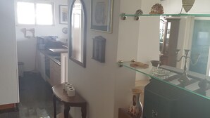 Una cocina con un banco de madera, una repisa de vidrio y un espejo.