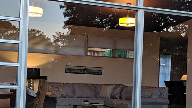 A modern living room with a sofa, a coffee table, and a mattress on a platform.
