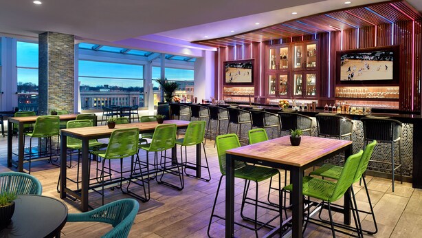 Um espaço de bar moderno com assentos e uma tela grande exibindo um evento esportivo.