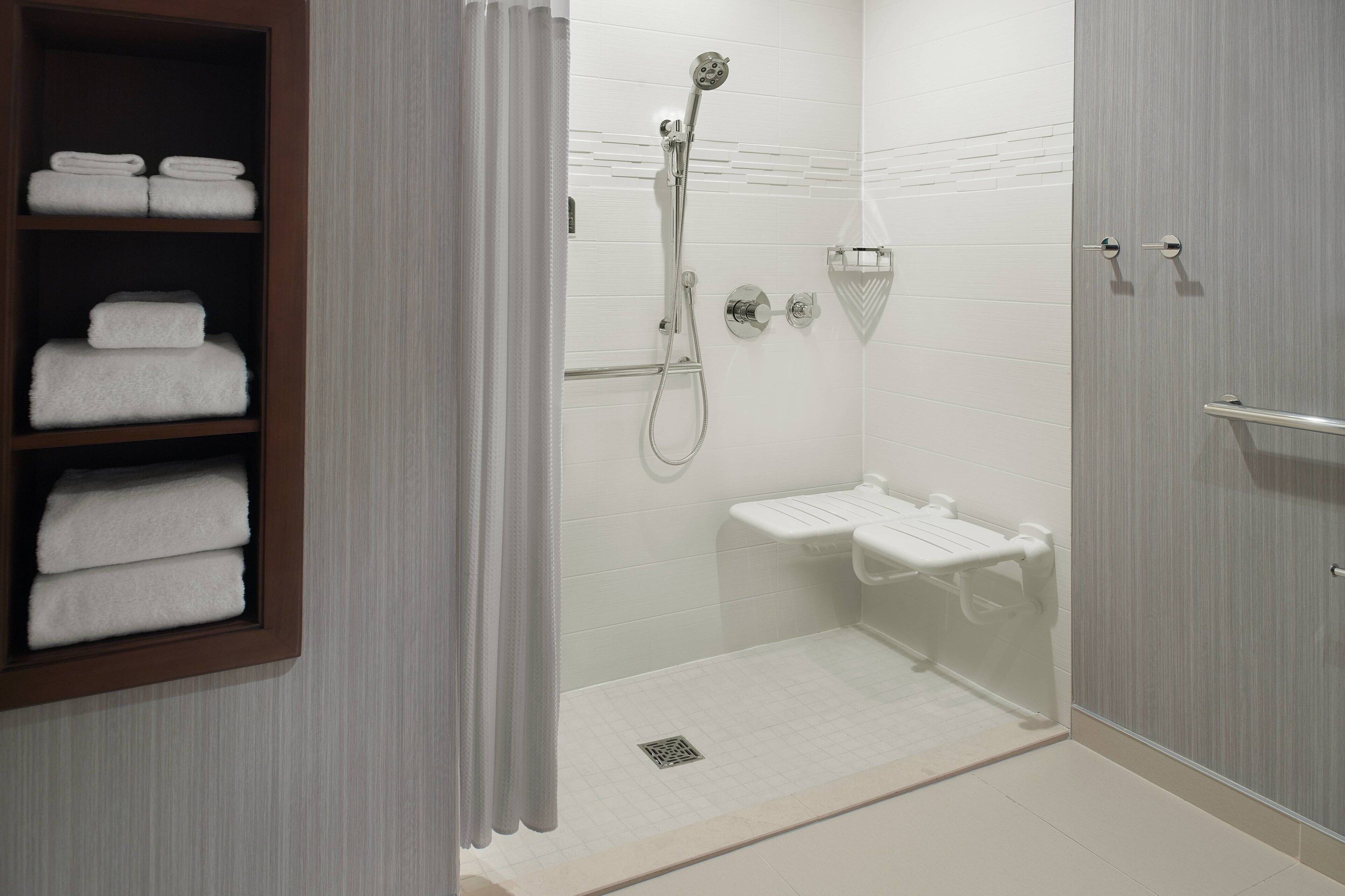 A modern bathroom with a glass shower enclosure, a built-in towel rack, and a white tiled floor.