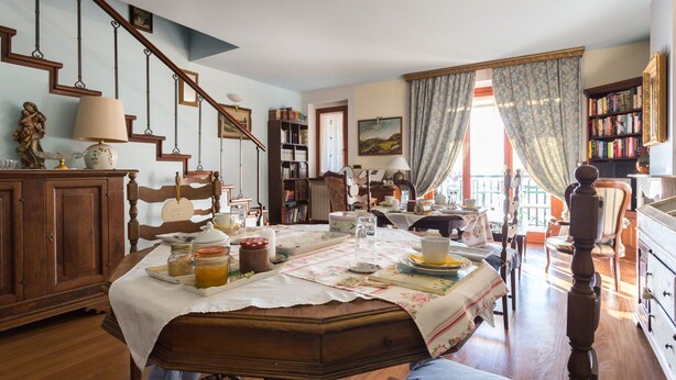 A cozy dining room with a wooden table set for a meal, surrounded by bookshelves and a staircase. - Holiday rental apartment Le Fate di Campagna (Assisi)