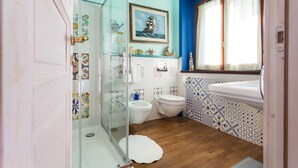 A bathroom with a glass shower enclosure, a toilet, a sink, and a window with curtains. - Holiday rental apartment Le Fate di Campagna (Assisi)