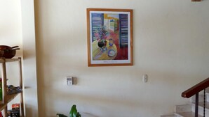 A staircase with a wooden handrail, a potted plant, and a framed painting on the wall. - Hotel Casa Vinculos (Esteli)