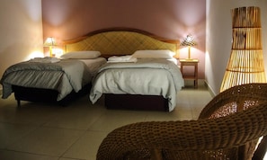 A room with two beds, a large woven chair, and two bedside lamps. - Hotel Casa Vinculos (Esteli)