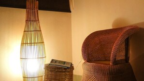 A wicker chair and a tall, cylindrical lamp with a woven design. - Hotel Casa Vinculos (Esteli)