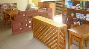 A children's play area with a brick play structure, a wooden table, and a shelf with snacks. - Hotel Casa Vinculos (Esteli)