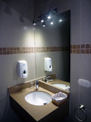 A bathroom with a large mirror, two sinks, and overhead lighting. - Hotel Casa Vinculos (Esteli)